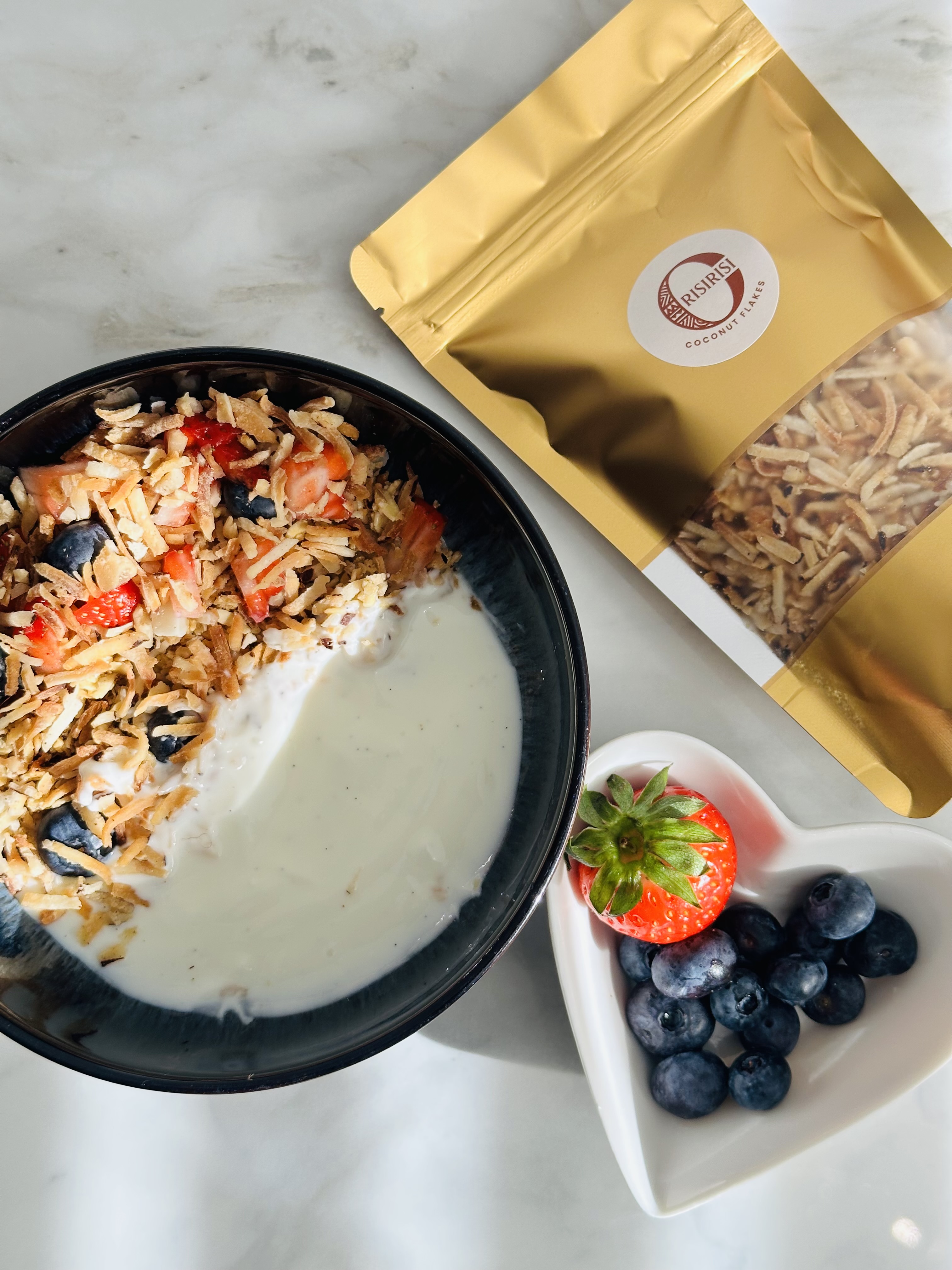 Orisirisi coconut flakes served on a yoghurt bowl with fresh berries